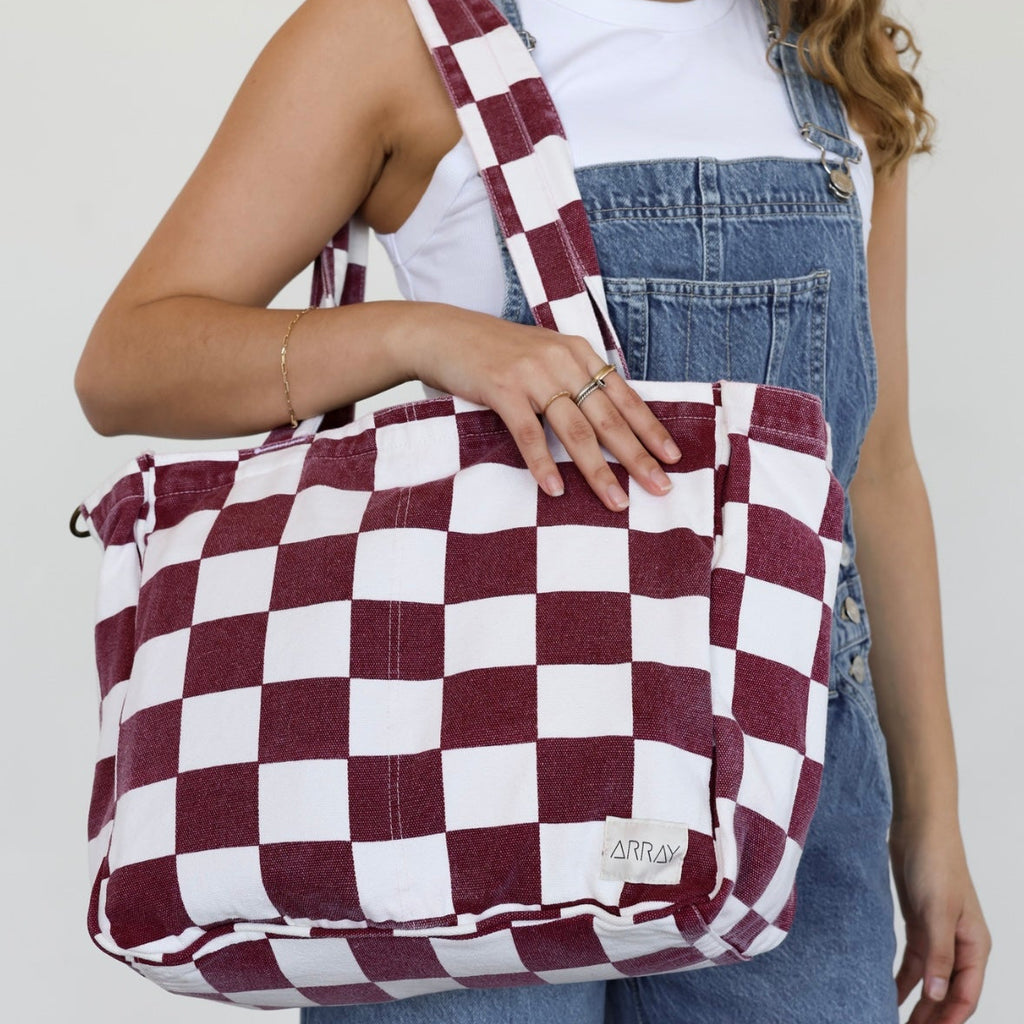 Person holding a red and white checkered bag against a plain background