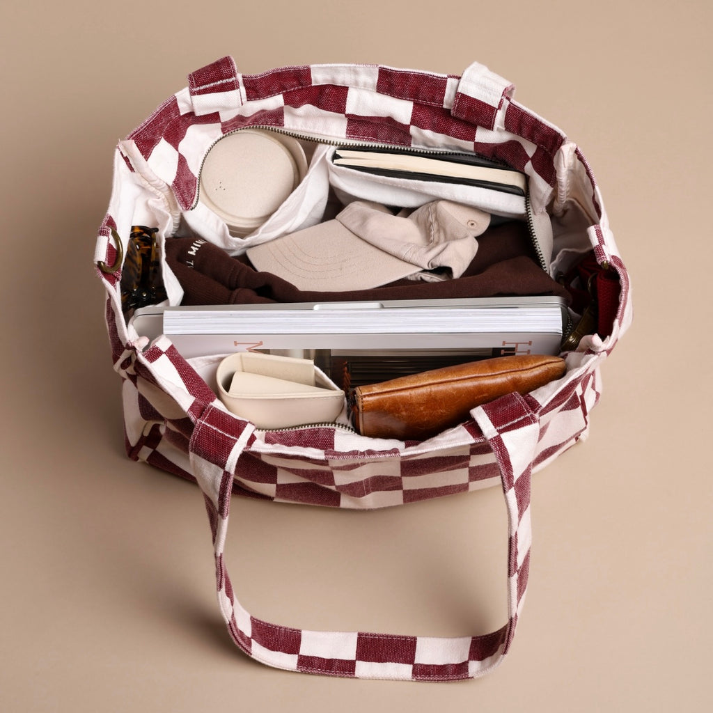 Checkered bag with various items on a beige background