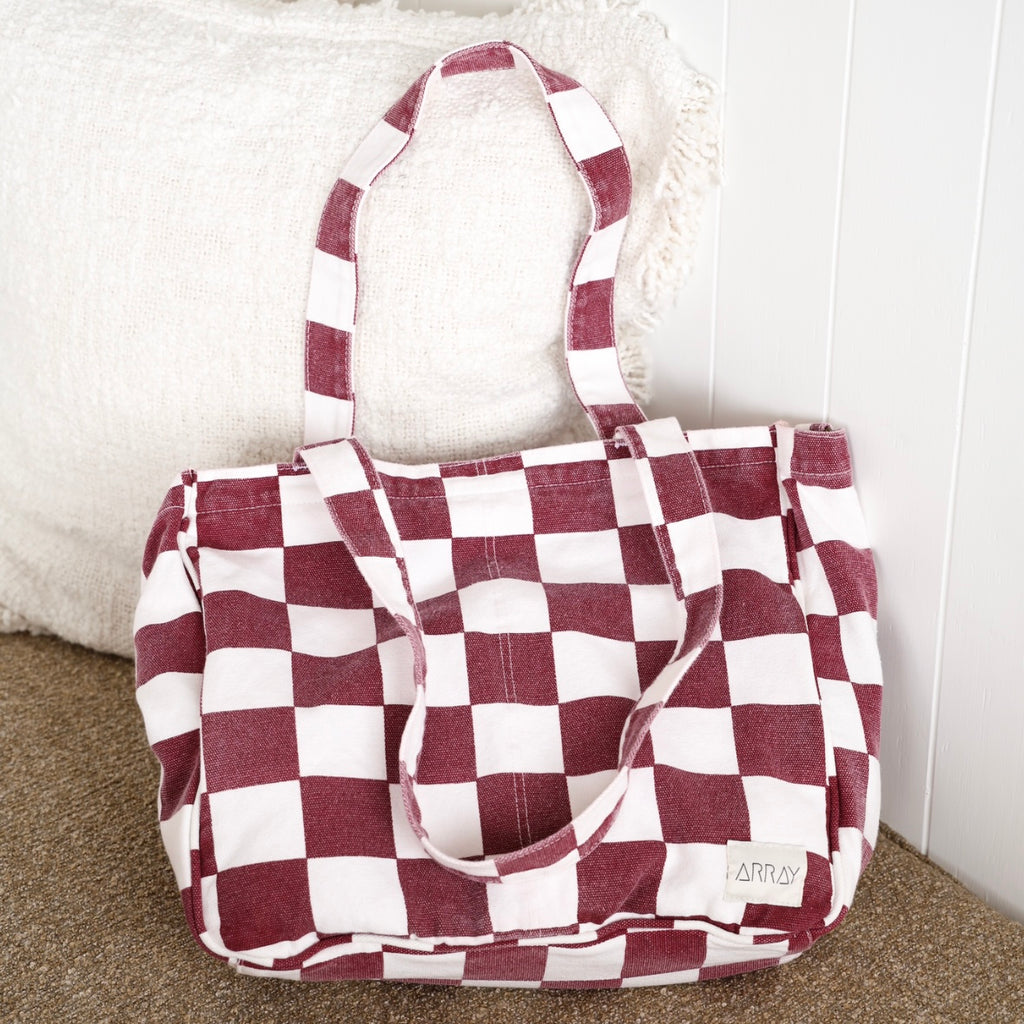 Red and white checkered bag on a carpeted floor with a white wall background