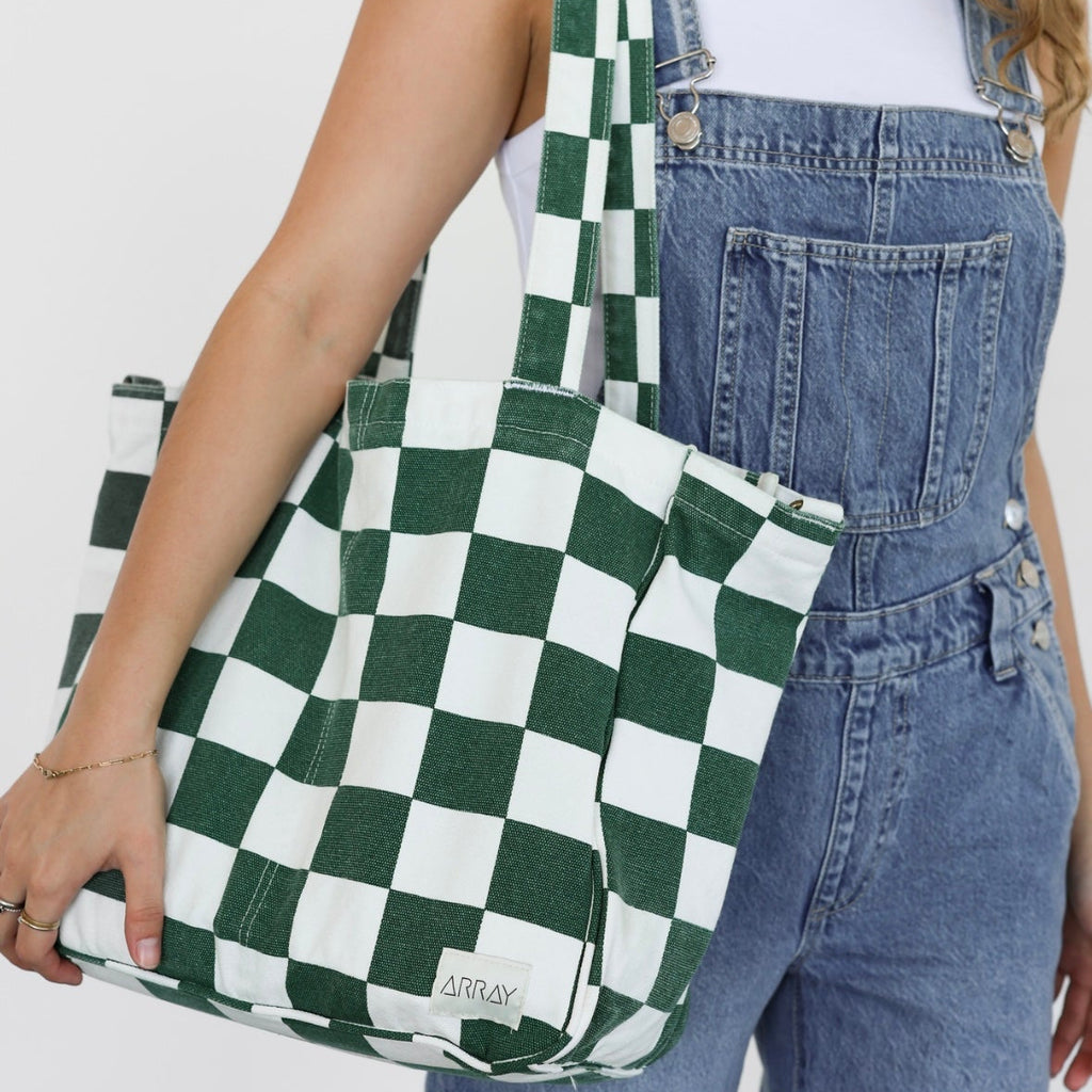 Person holding a green and white checkered bag with a plain background