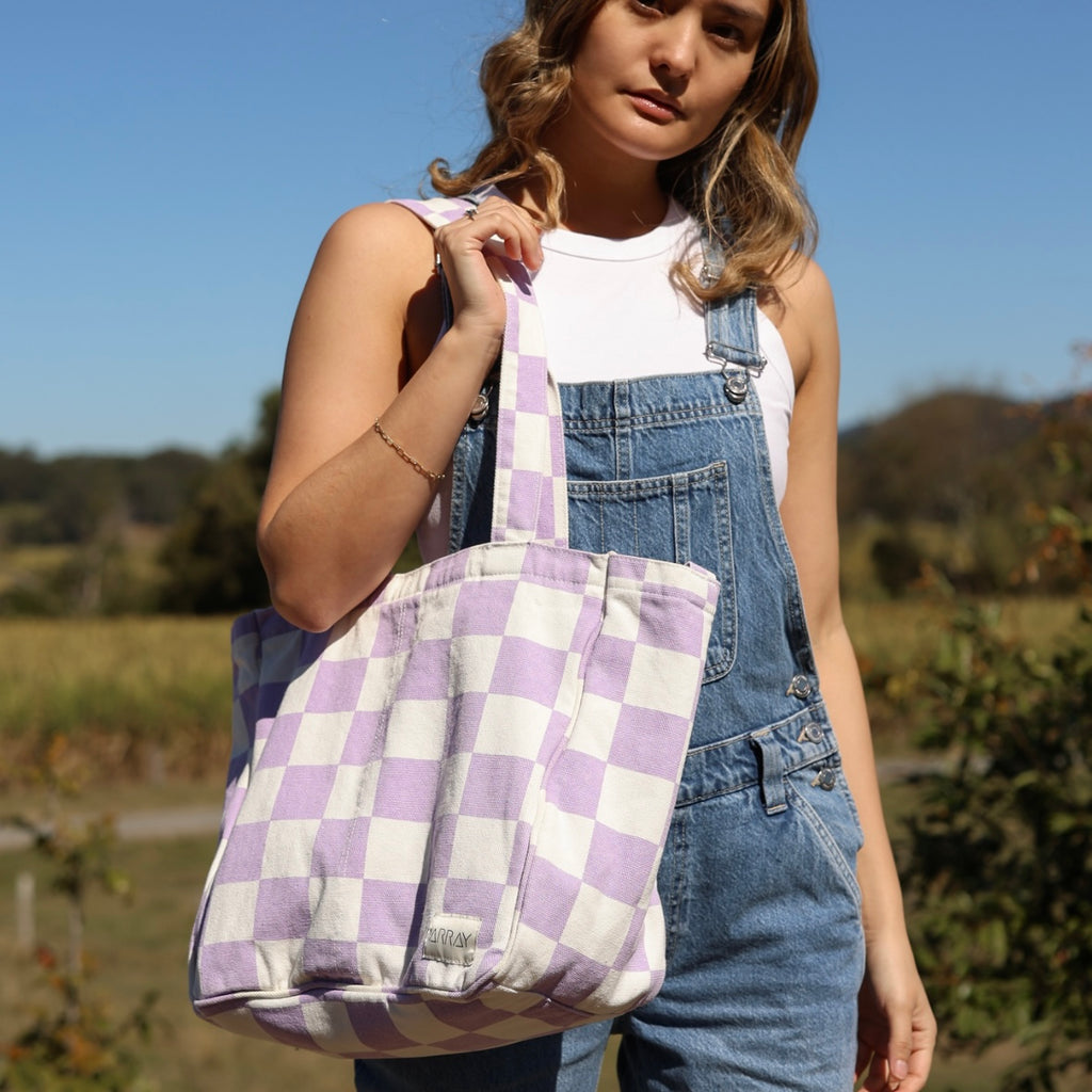 Person holding a purple and white checkered bag outdoors